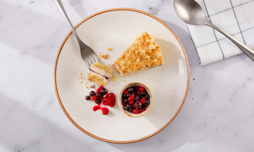 Bar and Block blueberry cheesecake with berries and crumble on a round cream plate with a fork