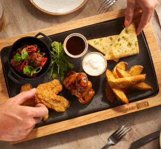 Bar and Block sharing starter with chicken goujons, sausages and chicken wings on a wooden platter