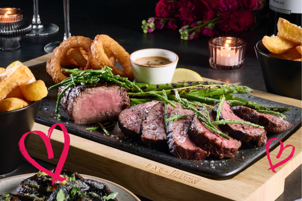 bar + block valentine's steak on table with rose flowers in background